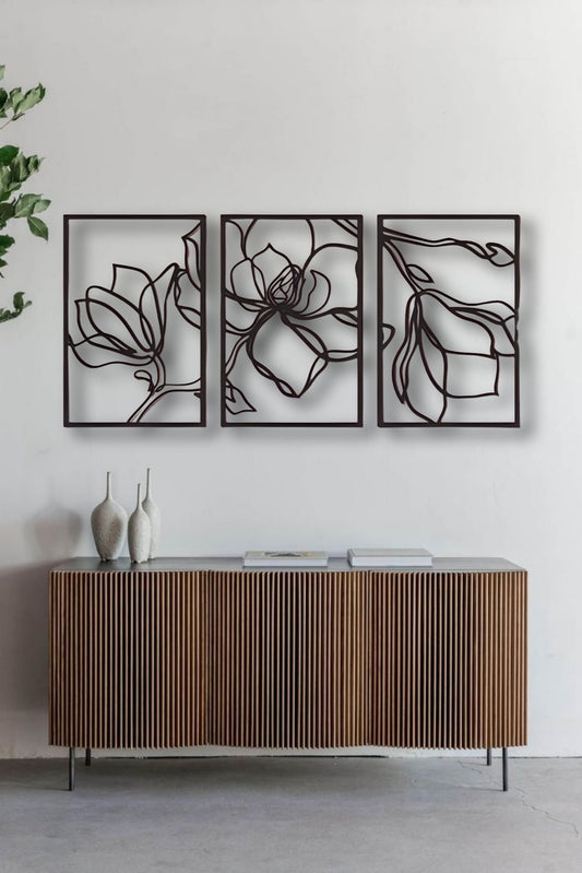 Three-piece floral wooden wall art in matte black finish mounted above a wooden slatted console table in a modern interior setting