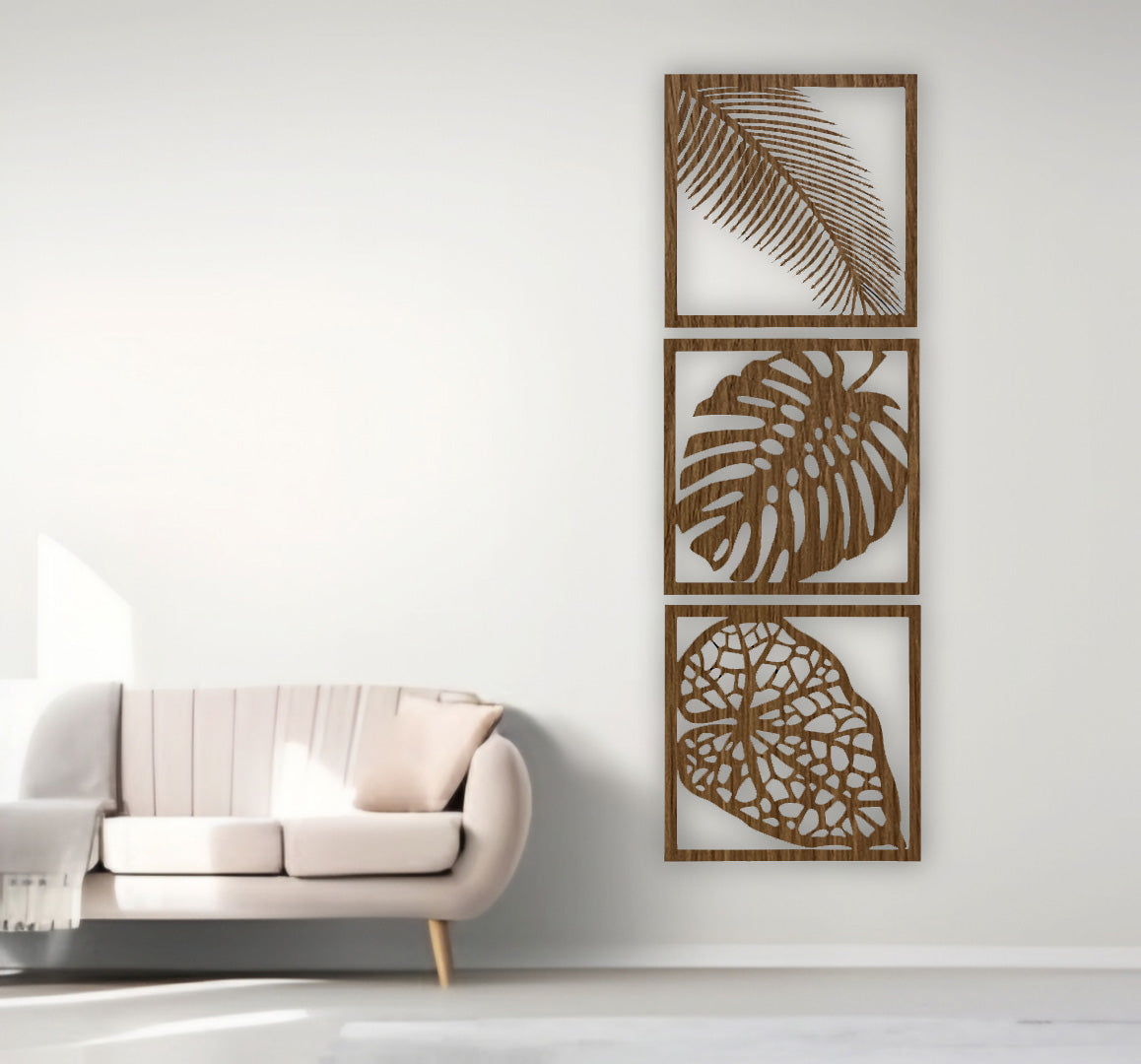 Three-piece vertical black wooden wall art set with palm, monstera, and vine leaf designs, mounted beside a cream sofa on a white wall.