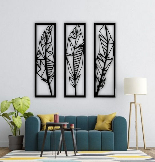 Modern black wooden wall art featuring a set of three vertical panels with abstract geometric feather designs, mounted on a light grey textured wall above a grey sofa.