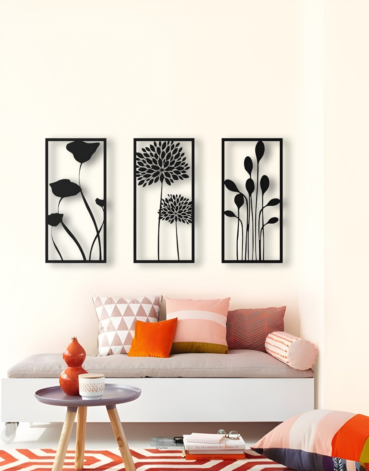 Three-piece botanical wooden wall art set in matte black finish, featuring floral silhouettes framed on a cream wall above a modern seating area with colorful pillows.
