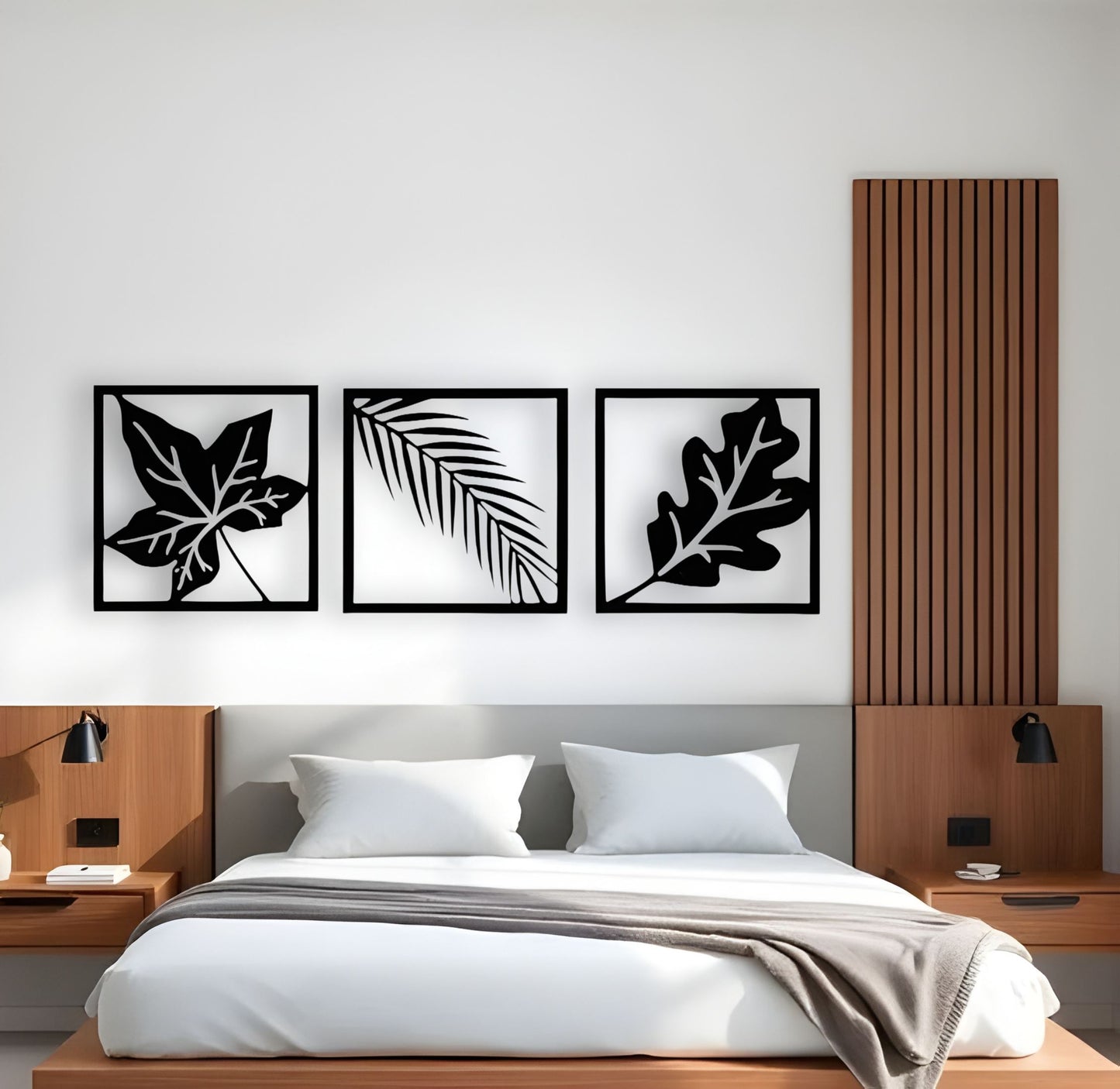 Modern wooden wall art in black featuring three framed botanical leaf designs mounted above a bed in a minimalist bedroom interior.