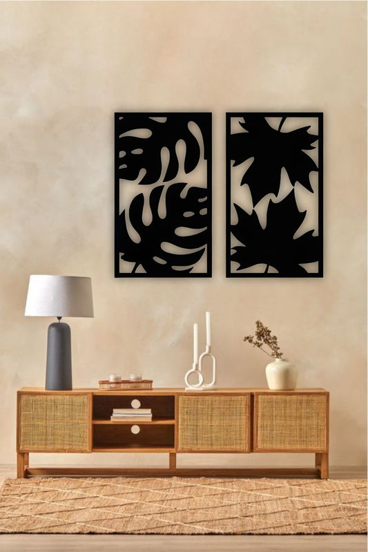 Set of two modern wooden wall art panels with leaf cutout designs displayed above a rattan console table in a cozy living room setting.