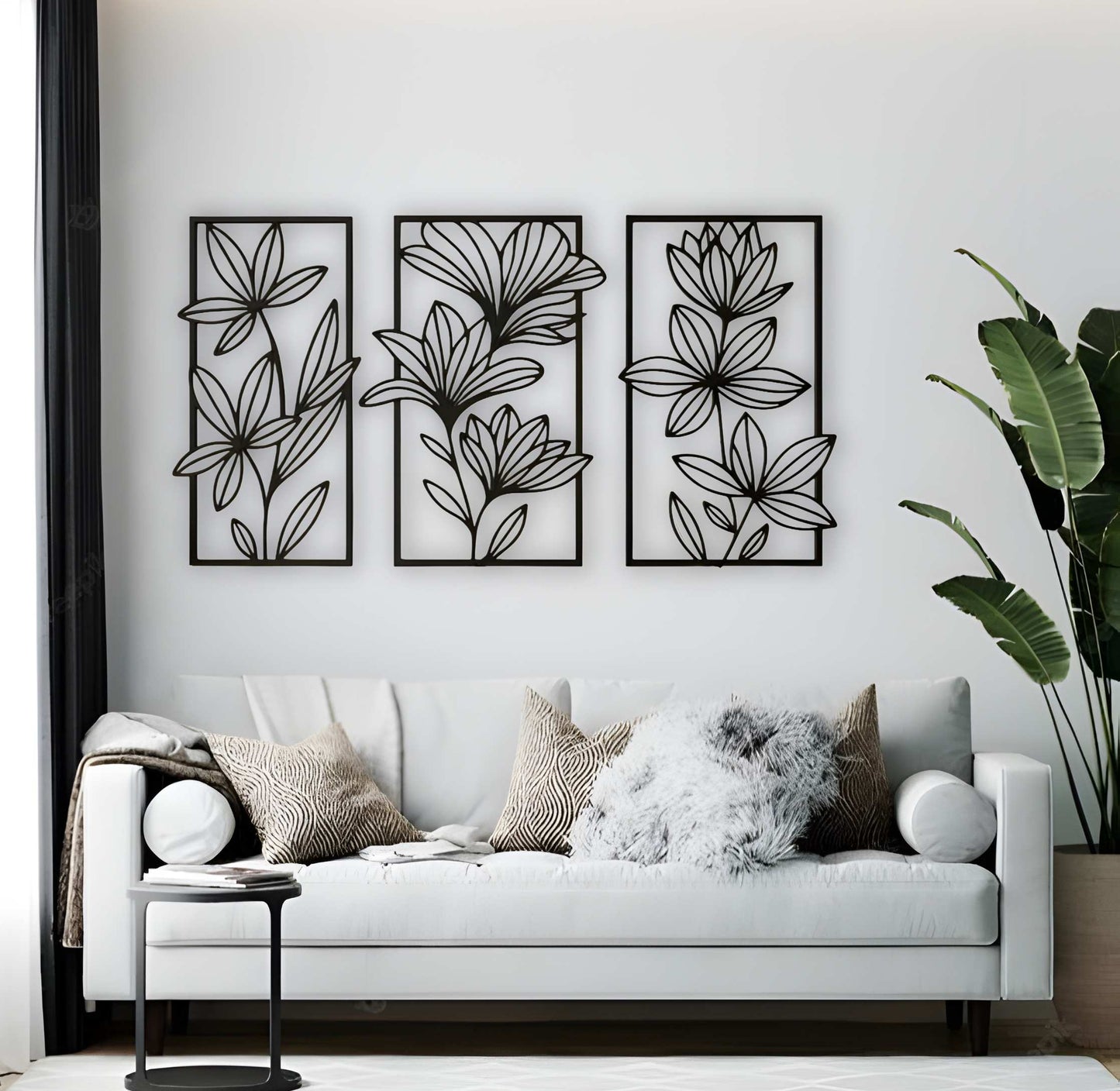 Three-piece floral wooden wall art set in matte black, mounted above a beige tufted sofa in a neutral-toned living room with cozy textures