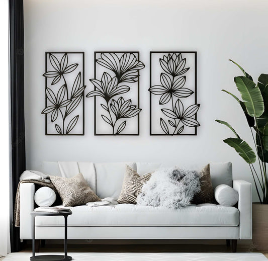 Three-piece floral wooden wall art set in matte black, mounted above a beige tufted sofa in a neutral-toned living room with cozy textures