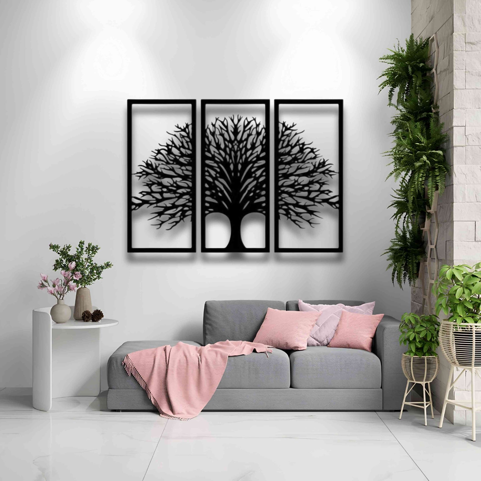 Three-piece black wooden Tree of Life wall art set mounted above a beige modern sofa, surrounded by indoor plants and minimalist decor.
