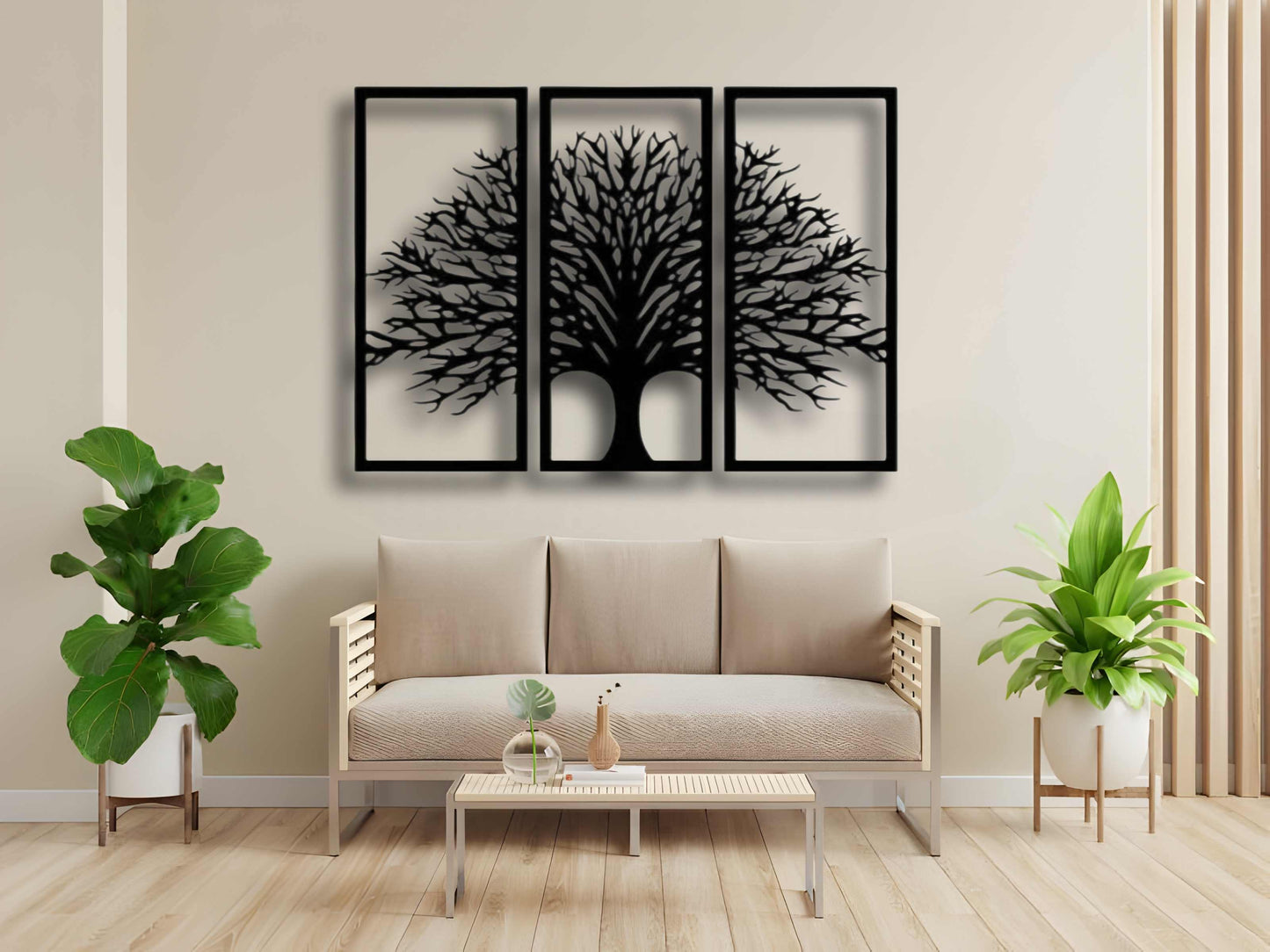 Three-piece black wooden Tree of Life wall art set mounted above a beige modern sofa, surrounded by indoor plants and minimalist decor.