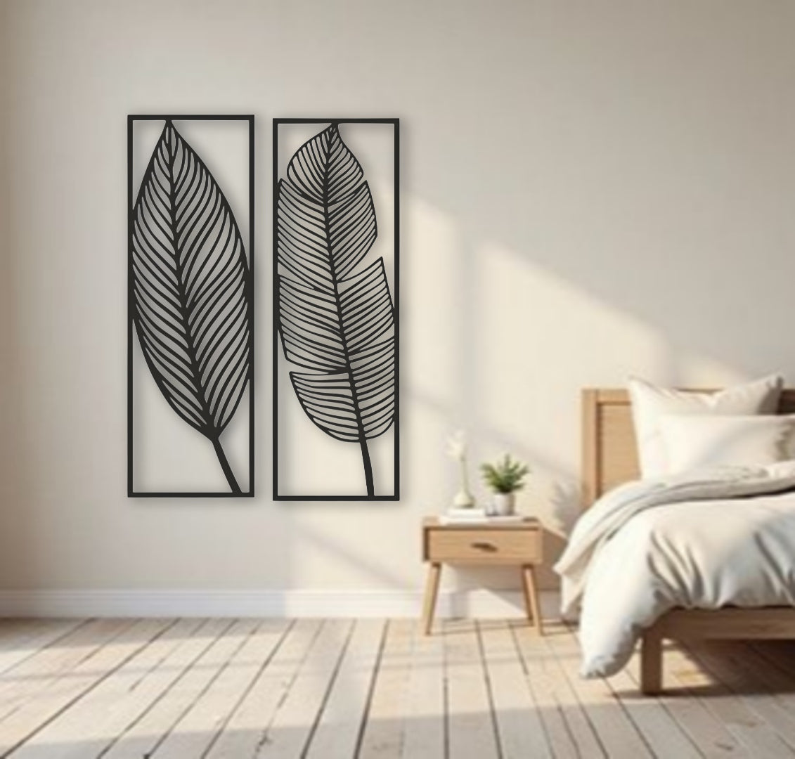 Two tall black wooden wall art panels with leaf designs, each 30 x 10 inches, mounted vertically above a sage green sectional in a modern living room