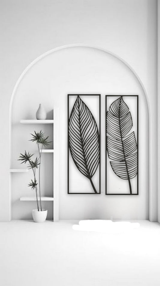 Two tall black wooden wall art panels with leaf designs, each 30 x 10 inches, mounted vertically above a sage green sectional in a modern living room