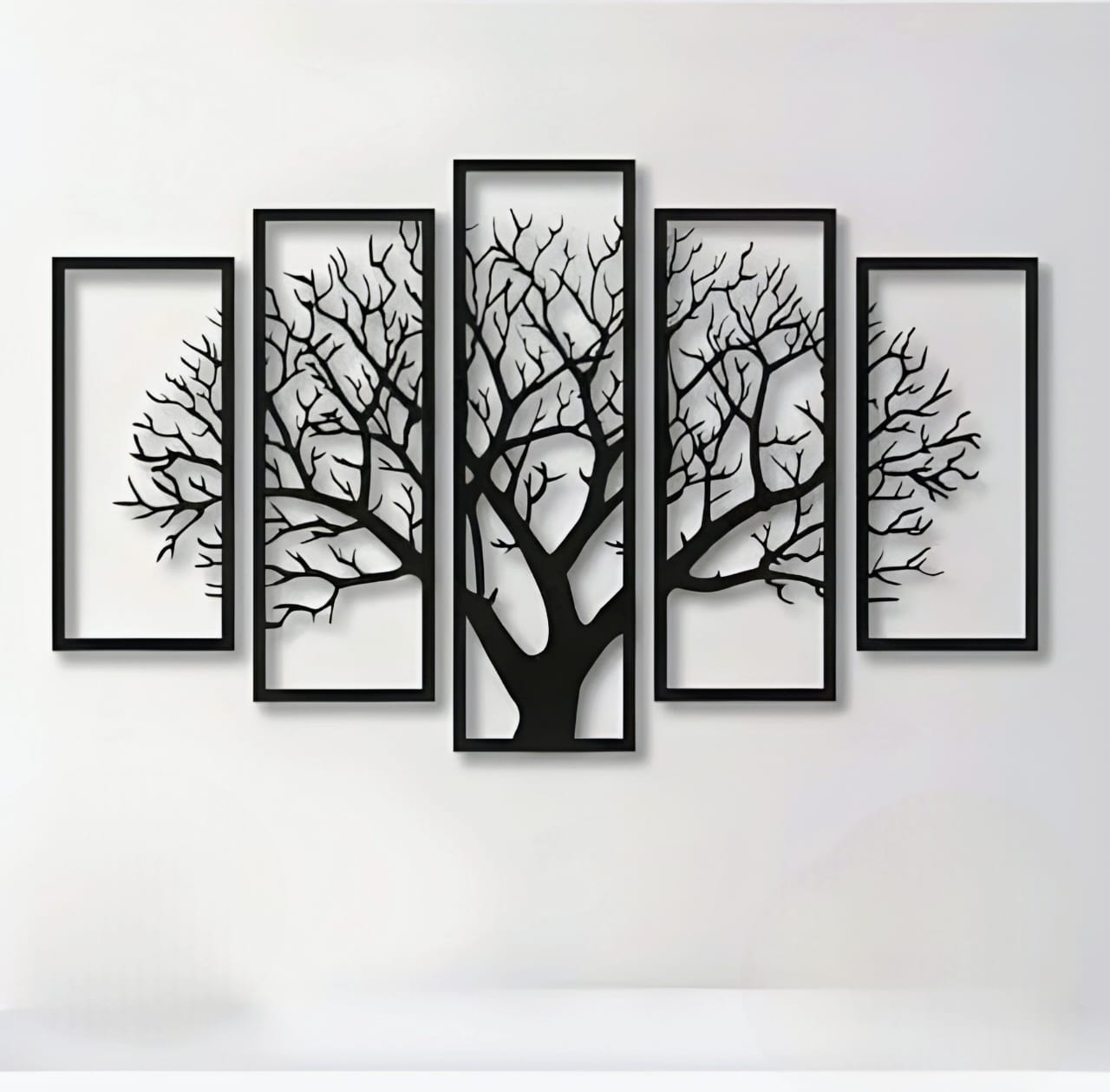 Set of five framed black tree silhouettes on a white wall
