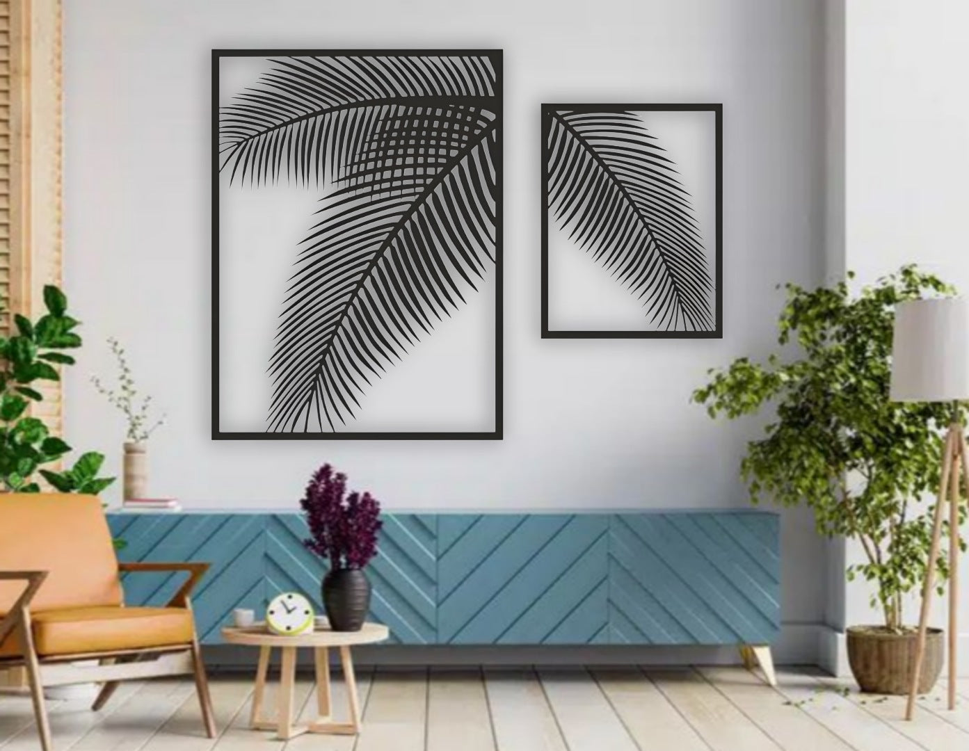 Two-piece black wooden palm leaf wall art set mounted on a blue wall above a modern blue sofa with indoor tropical plants.