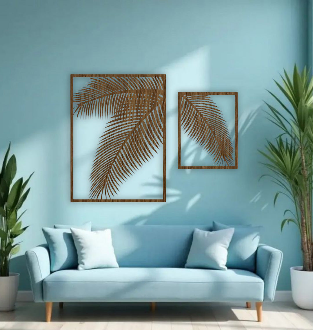 Two-piece black wooden palm leaf wall art set mounted on a blue wall above a modern blue sofa with indoor tropical plants.