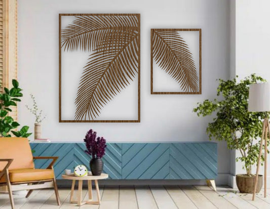 Two-piece black wooden palm leaf wall art set mounted on a blue wall above a modern blue sofa with indoor tropical plants.