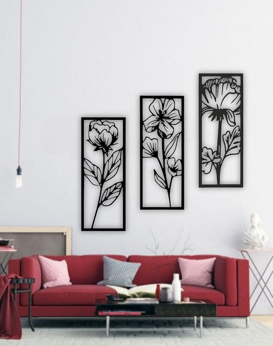 Set of three vertical floral wall art panels in black wooden finish, displayed above a red modern sofa in a stylish living room setting.