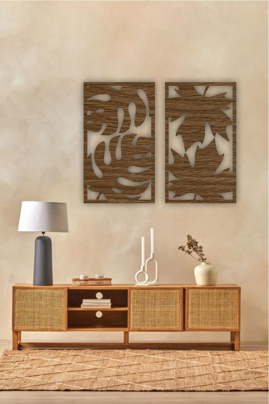 Set of two modern wooden wall art panels with leaf cutout designs displayed above a rattan console table in a cozy living room setting.