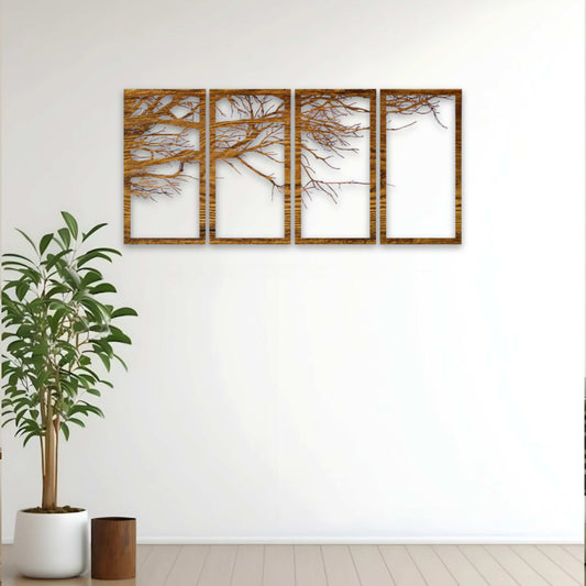 Set of four framed tree silhouettes on a white wall with a plant on the left.