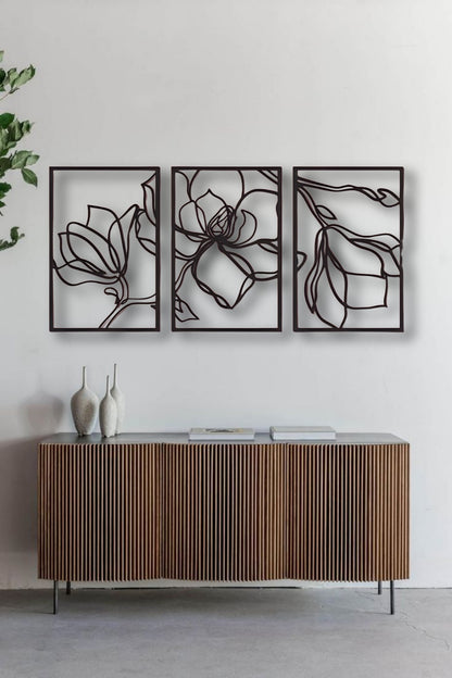 Three-piece floral wooden wall art in matte black finish mounted above a wooden slatted console table in a modern interior setting