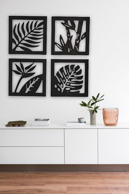“Four-piece square wooden wall art set with tropical leaf and plant designs in black finish, mounted above a modern wooden sideboard.”