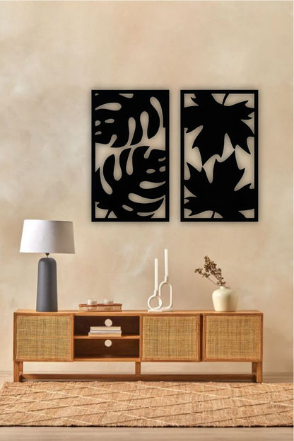 Set of two modern wooden wall art panels with leaf cutout designs displayed above a rattan console table in a cozy living room setting.
