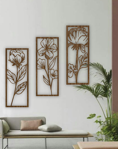 Three-piece floral wall art panels in natural wood brown finish, mounted on a white wall in a minimalist room with indoor plants.