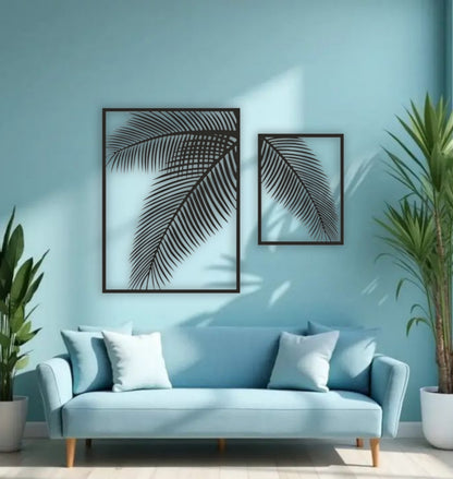 Two-piece black wooden palm leaf wall art set mounted on a blue wall above a modern blue sofa with indoor tropical plants.