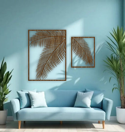 Two-piece black wooden palm leaf wall art set mounted on a blue wall above a modern blue sofa with indoor tropical plants.