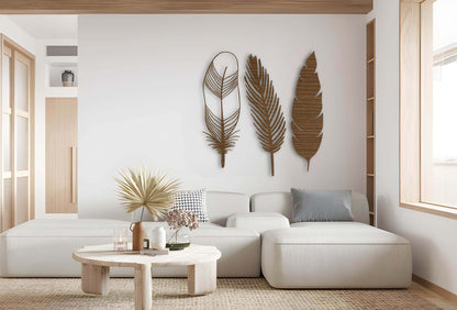 Set of three wooden feather wall decorations in natural brown finish, bringing warmth and rustic charm to a neutral interior backdrop.