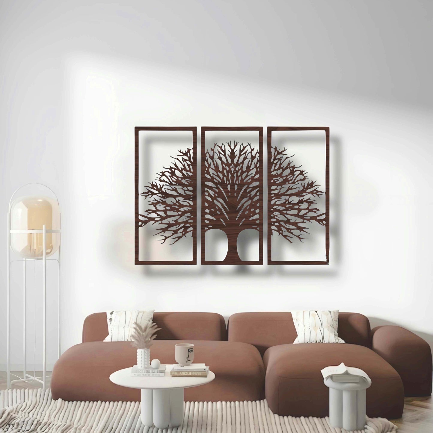 Three-piece black wooden Tree of Life wall art set mounted above a beige modern sofa, surrounded by indoor plants and minimalist decor.