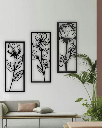 Set of three vertical floral wall art panels in black wooden finish, displayed above a red modern sofa in a stylish living room setting.