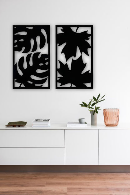 Set of two modern wooden wall art panels with leaf cutout designs displayed above a rattan console table in a cozy living room setting.