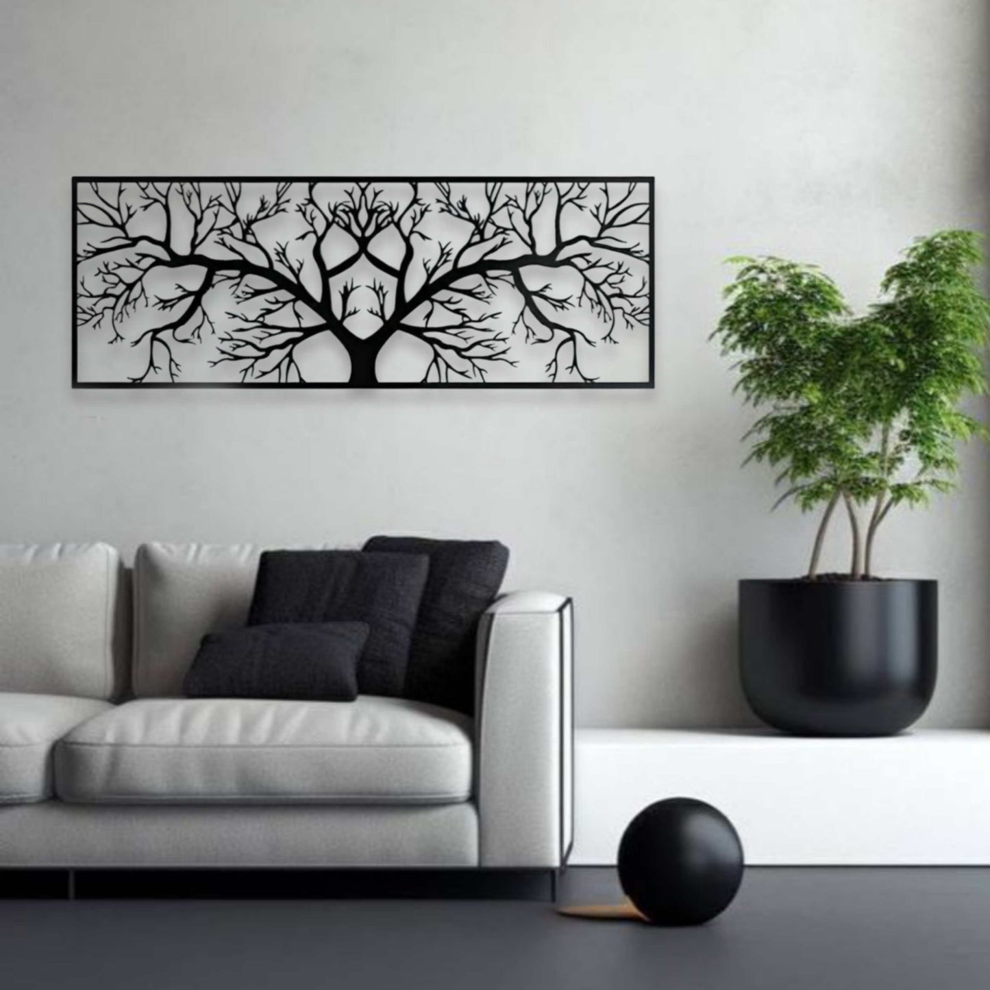 Modern living room with a black tree branch wall art, gray sofa, and potted plant.